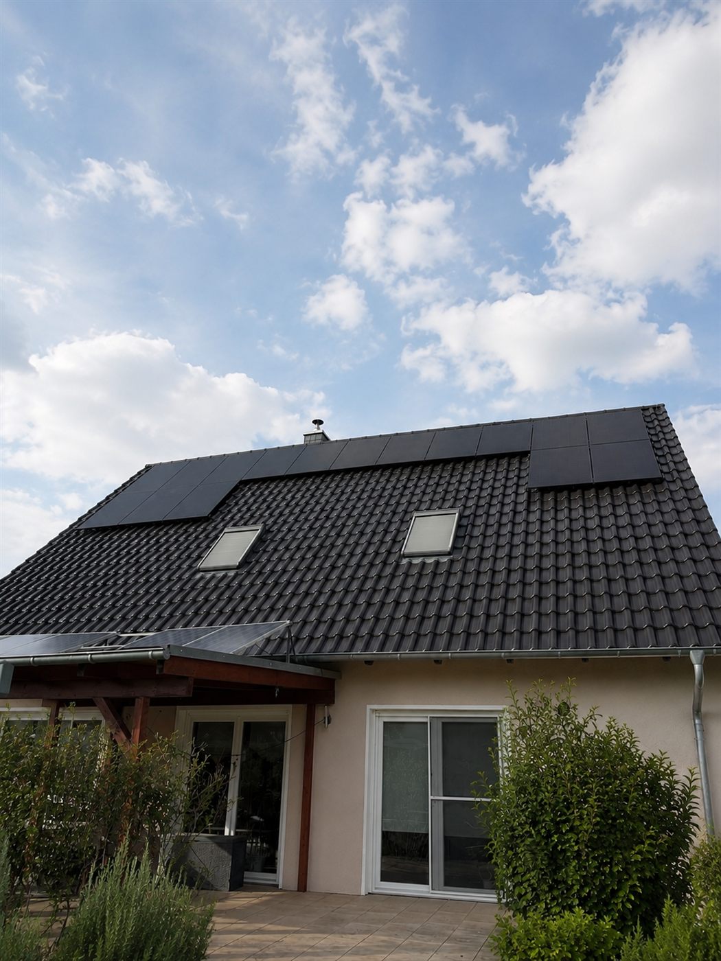Anthrazitfarbenes Satteldach mit Photovoltaik-Modulen und zusätzlich solarbelegter Terrassenüberdachung