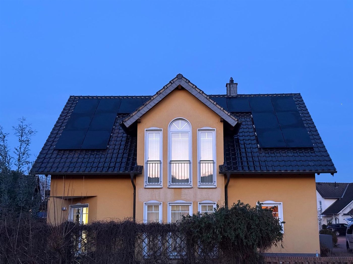 Einfamilienhaus in der Dämmerung mit Photovoltaik-Modulen auf beiden Dachflächen