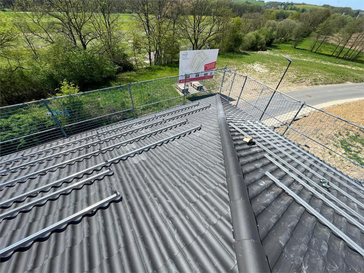 Montageschienen auf einem Ziegeldach während der Installation, Dachfläche mit Sicherungsnetz abgesichert