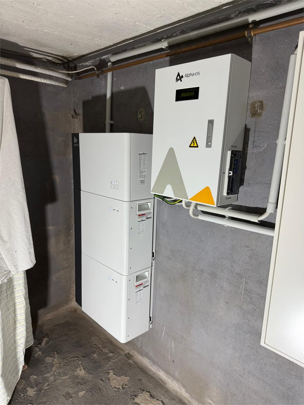 Batteriespeicher im Kellerraum mit daneben an der Wand montiertem Hybrid-Wechselrichter